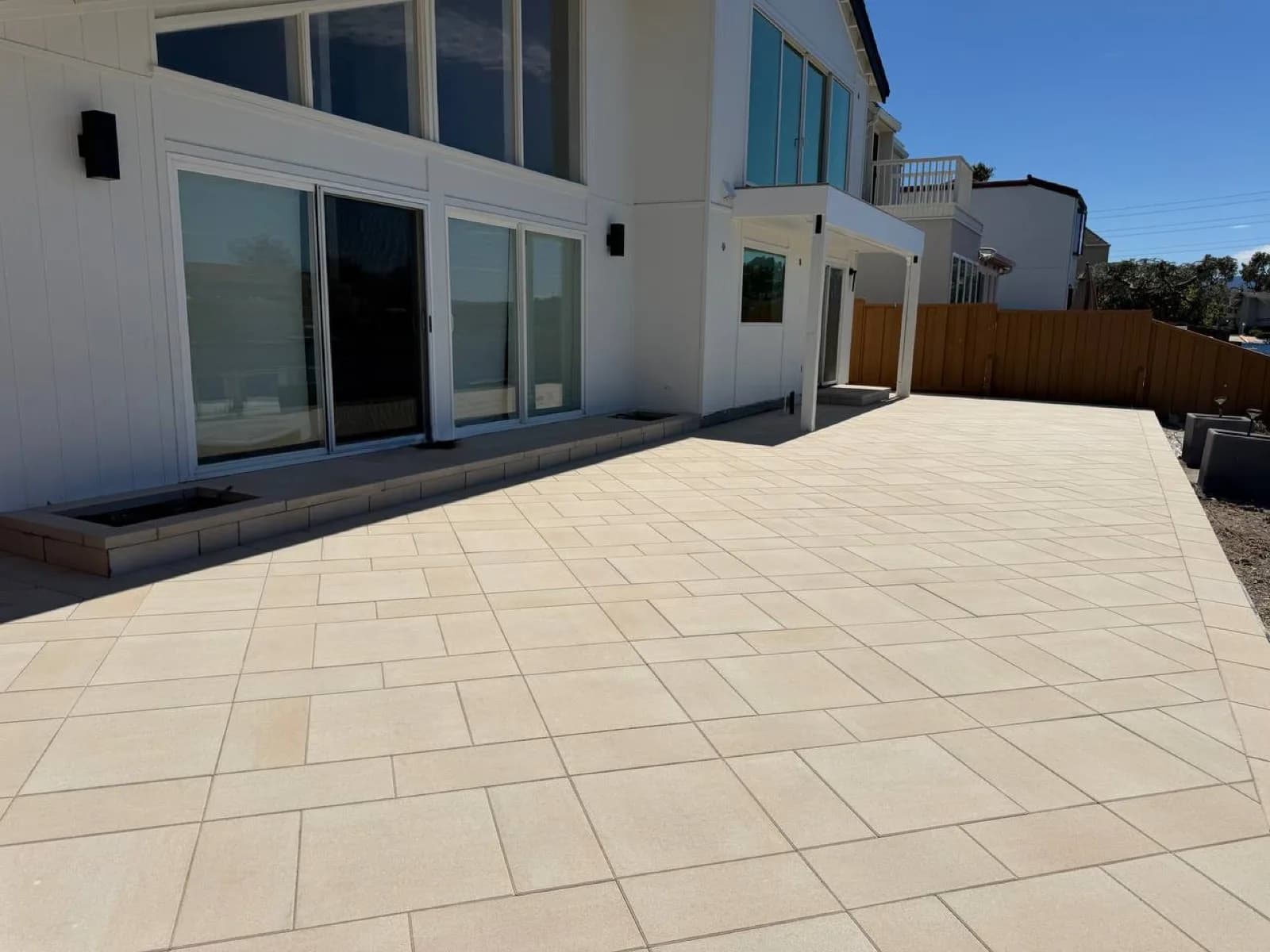 Large-format cream porcelain paver patio along the back of a white two-storey home