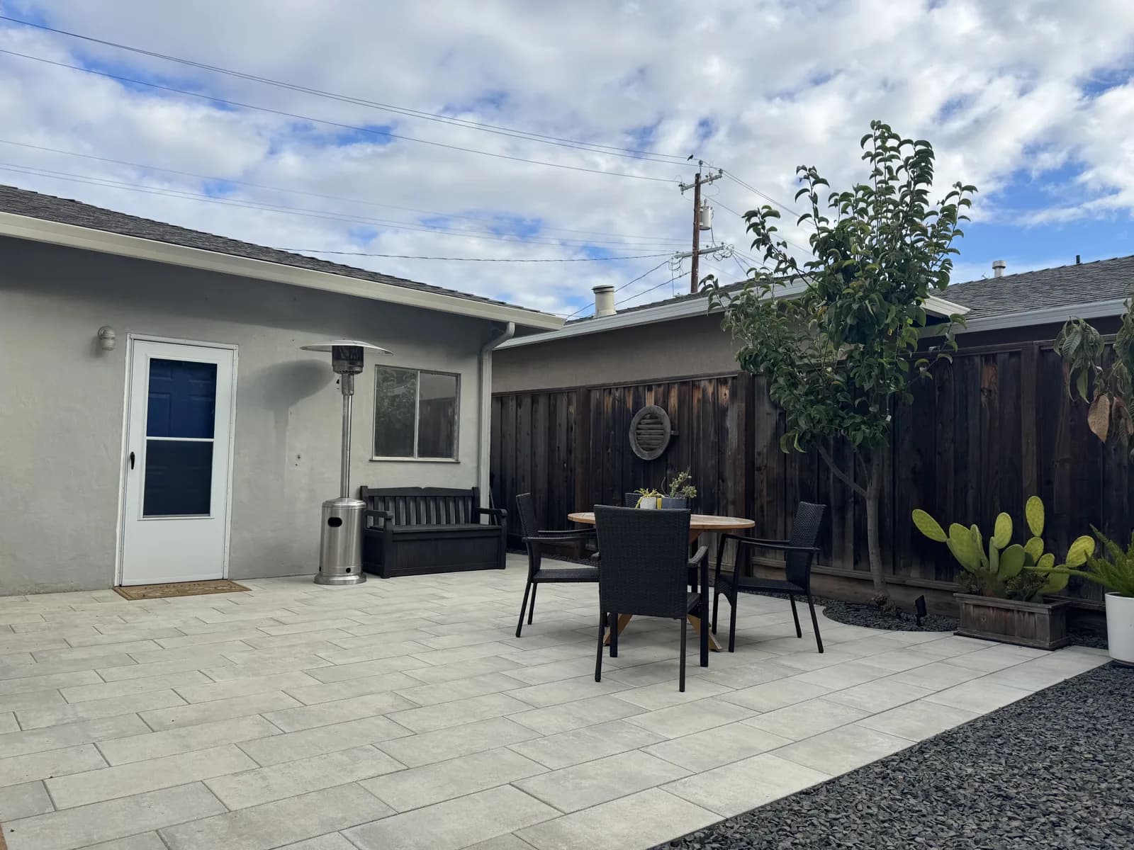 Grey large-format paver patio with a dining set and a gravel border beside the house
